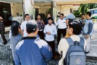 Sejumlah aktivis Forum Rakyat NTB berdiri di depan proyek gedung layanan pendidikan Poltekkes Mataram yang tampak terbengkalai, dengan material bangunan berserakan dan tanpa aktivitas konstruksi. (Foto: Istimewa)