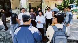 Sejumlah aktivis Forum Rakyat NTB berdiri di depan proyek gedung layanan pendidikan Poltekkes Mataram yang tampak terbengkalai, dengan material bangunan berserakan dan tanpa aktivitas konstruksi. (Foto: Istimewa)