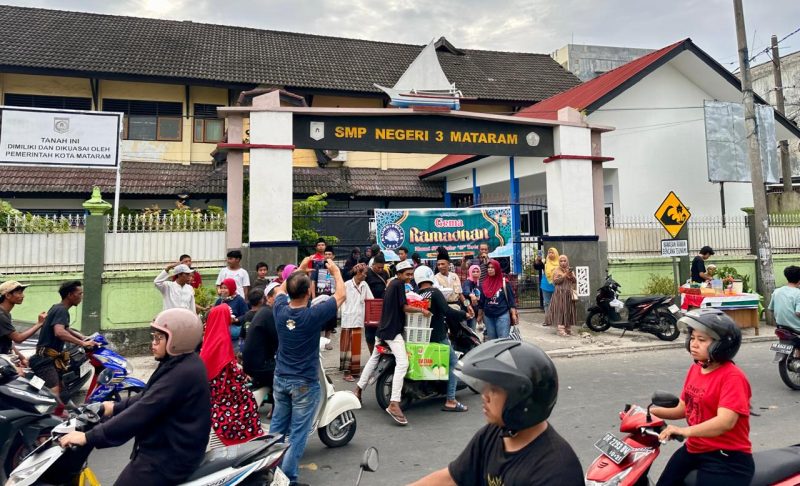 Para alumni SMPN 3 Mataram angkatan 1987 membagikan paket takjil kepada warga di depan Pasar ACC, Ampenan, Minggu (16/3/2025). (Foto: Istimewa)