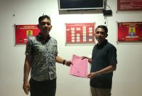 Seorang pria sedang berdiri di depan kantor polisi sambil menunjukkan berkas laporan, melaporkan dugaan pemerasan oleh debt collector. (Foto: Istimewa)