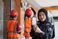 Petugas PLN memamerkan kemudahan layanan melalui aplikasi PLN Mobile saat mendampingi pekerjaan teknis di lapangan. (Foto: Dok. PLN)