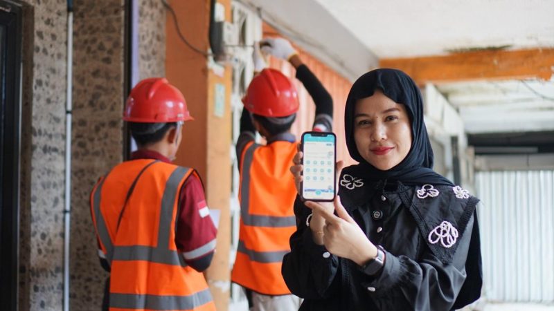Petugas PLN memamerkan kemudahan layanan melalui aplikasi PLN Mobile saat mendampingi pekerjaan teknis di lapangan. (Foto: Dok. PLN)