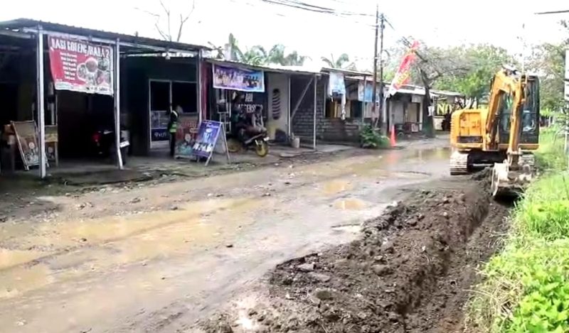Sebuah alat berat dikerahkan untuk melakukan penggalian saluran drainase di sepanjang jalan utama yang rusak dan berlumpur di kawasan pemukiman padat. Proyek ini diharapkan dapat mengurangi genangan air dan memperbaiki infrastruktur jalan demi kenyamanan warga sekitar. (Foto: Istimewa)