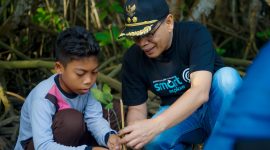 Seorang anak dibimbing oleh perwakilan pemerintah saat menanam bibit mangrove di kawasan ekowisata Bale Mangrove, Jerowaru, Lombok Timur. Aksi ini menjadi bagian dari peringatan Hari Mangrove Sedunia dan wujud nyata edukasi lingkungan kepada generasi muda dalam program pemberdayaan desa berbasis konservasi yang didukung PLN. (Foto: Dok. PLN)