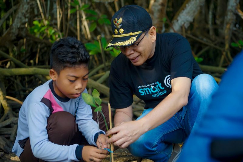 Seorang anak dibimbing oleh perwakilan pemerintah saat menanam bibit mangrove di kawasan ekowisata Bale Mangrove, Jerowaru, Lombok Timur. Aksi ini menjadi bagian dari peringatan Hari Mangrove Sedunia dan wujud nyata edukasi lingkungan kepada generasi muda dalam program pemberdayaan desa berbasis konservasi yang didukung PLN. (Foto: Dok. PLN)