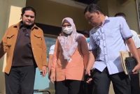 Dewi Noviany keluar dari ruang penyidikan dengan pengawalan petugas, usai ditetapkan sebagai tersangka korupsi masker. (Foto: Istimewa)