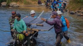 pekerja mengangkut panel surya menyeberangi sungai,
Upaya PLN menghadirkan listrik hingga pelosok negeri distribusi panel surya ke wilayah terpencil. (Foto: Dok. PLN)