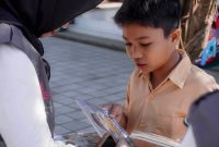 Seorang anak antusias membaca buku yang dibagikan relawan Program Desa Berdaya PLN NTB dalam kampanye literasi di Desa Medana. (Dok. PLN)
