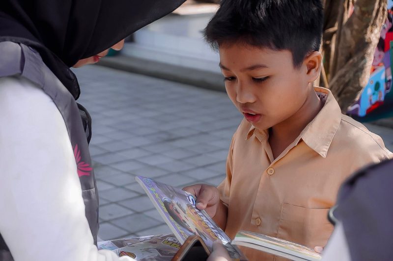 Seorang anak antusias membaca buku yang dibagikan relawan Program Desa Berdaya PLN NTB dalam kampanye literasi di Desa Medana. (Dok. PLN)