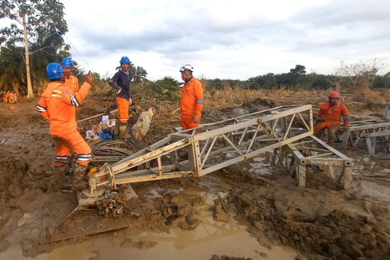 Tim PLN bekerja di tengah lumpur tebal untuk membangun ulang struktur tower dan memperbaiki jaringan transmisi yang terdampak banjir. (Dok. PLN)