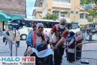 Petugas PPIH menyambut dan membantu Jemaah Haji Kloter 3 asal Lombok Barat saat tiba di Asrama Haji Mataram usai menunaikan ibadah haji di Tanah Suci, Kamis (4/6/2026). (Foto: Istimewa)