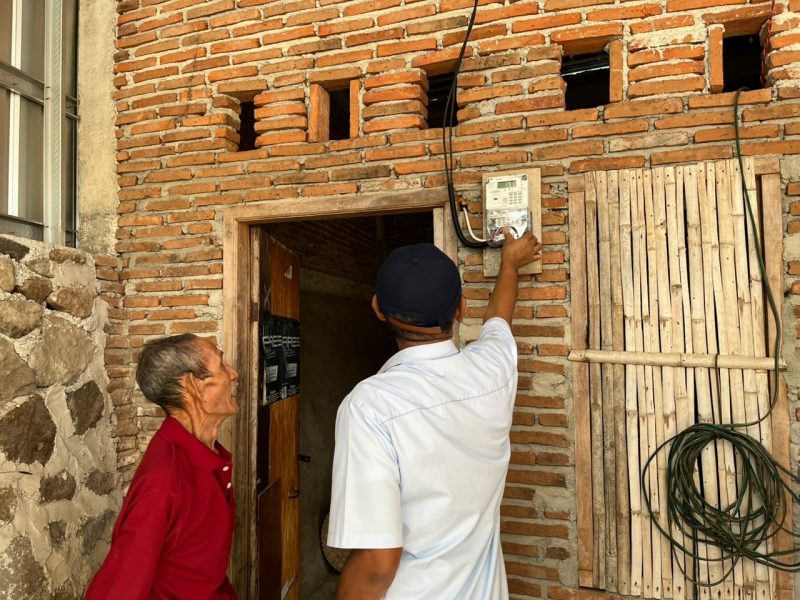 Caption: Petugas PLN memastikan sambungan listrik di rumah warga telah terpasang sebagai bagian dari program kepedulian YBM PLN.(Foto: Istimewa 